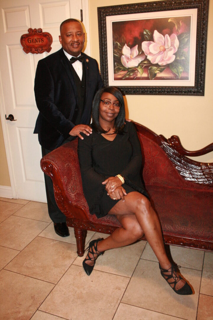 A man and woman posing for the camera on a couch.